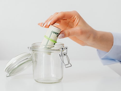 This image represents savings accounts, showing money being placed in a jar. 